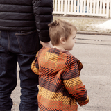 A dad holds a child's hand to cross the street